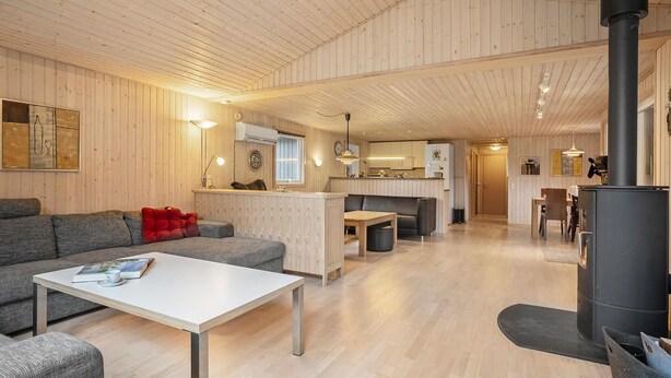 Un acogedor interior de cabaña con sala de estar, cocina y estufa de leña.