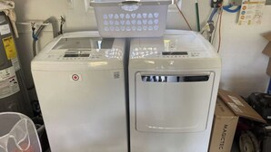 Deux machines à laver blanches, chacune surmontée d’un panier, entourées de divers objets et équipements.