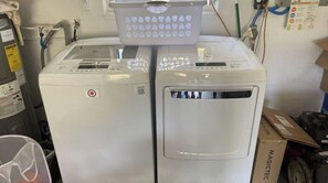 Two white washing machines with a basket on top, surrounded by various items and equipment.