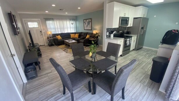 Un salon moderne comprenant un canapé, une table basse et un coin repas avec des chaises.