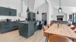 Una cocina moderna con una isla central, taburetes de bar e iluminación colgante.