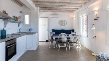 A compact kitchen with white cabinetry, a built-in oven, and a dining area with a table and chairs.