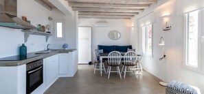 Une cuisine compacte avec des meubles blancs, un four encastré et un coin repas comprenant une table et des chaises.