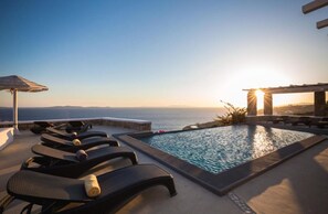 A poolside area with lounge chairs and a view of the sea at sunset. - Stunning 2BR Cottage With Private Pool in Mykonos (Mykonos)
