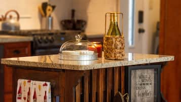 Un comptoir de cuisine avec une bouteille de vin, une bougie et une citation encadrée.