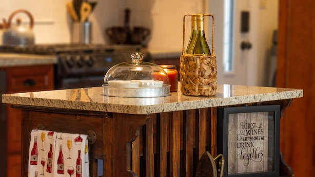 Una encimera de cocina con una botella de vino, una vela y un cartel enmarcado.