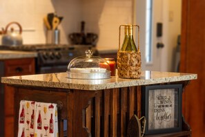 Una encimera de cocina con una botella de vino, una vela y un cartel enmarcado.
