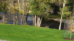 Un área verde bien cuidada con un sendero de grava, árboles y una masa de agua.