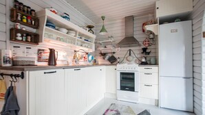 Una cocina compacta con armarios blancos, una estufa, un refrigerador y diversos utensilios y electrodomésticos.