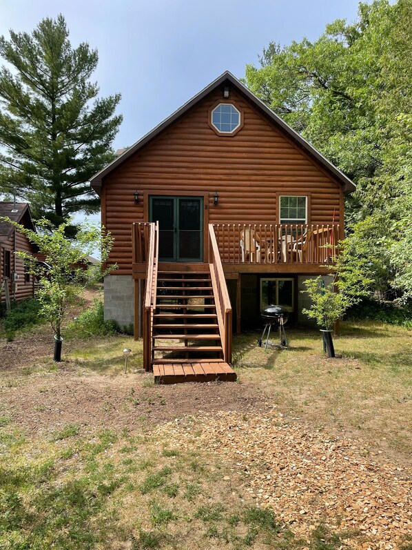 Une cabane en bois avec un porche à l’avant, un escalier et une petite terrasse.