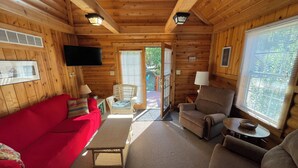 Interior acogedor de una cabaña con un sofá rojo, sillones de mimbre y un sillón marrón.