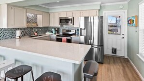 Una cocina moderna con una isla central, electrodomésticos de acero inoxidable y muebles de color claro.