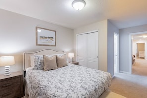 A bedroom with a bed, nightstands, a framed picture, and a closet.