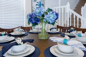 A dining table set with white plates, blue napkins, and a vase of blue flowers. - Large Home w/ Private pool, Clubhouse, Near Parks (Kissimmee)