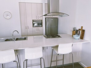 A modern kitchen with a central island, stainless steel appliances, and white cabinetry.