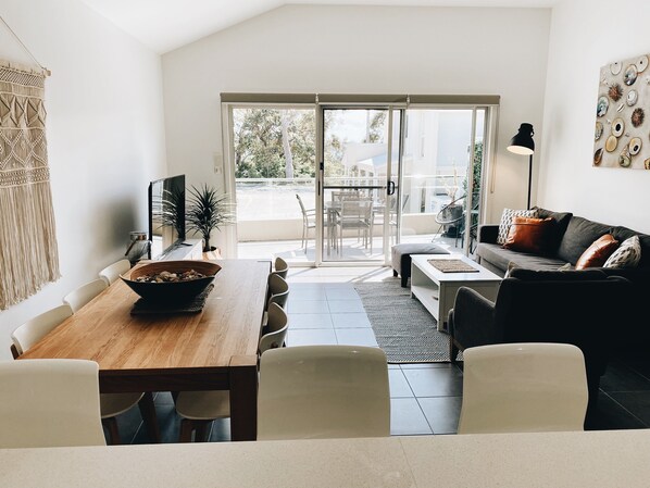 A modern living room with a dining area, a sofa, and a TV.
