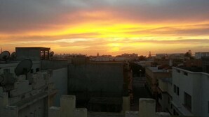 A sunset view from a rooftop with buildings in the background.