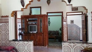 A living room with a TV, sofa, and patterned tiles.