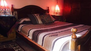 A neatly made bed with a striped blanket, two bedside tables with lamps, and a wooden headboard.