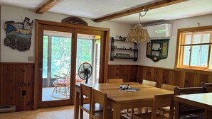 Un comedor acogedor con una mesa y sillas de madera, una araña y vistas al exterior a través de un ventanal.