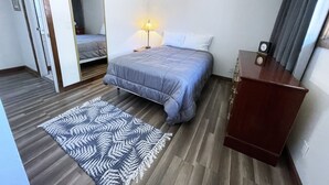 A bedroom with a bed, bedside lamp, wooden floor, and a mirror. - Comfortable Gonzaga unit close to downtown Spokane (Spokane)