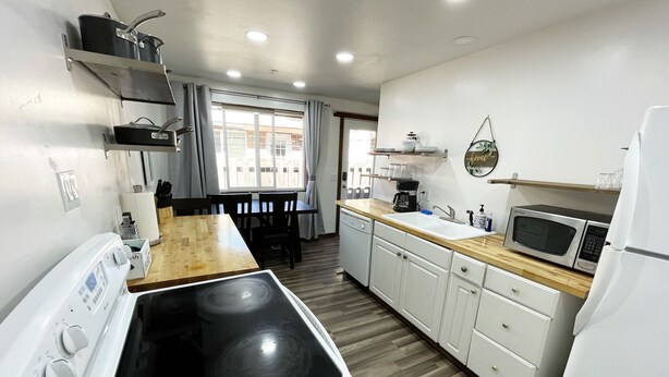 A compact kitchen with a stove, microwave, and white cabinets. - Comfortable Gonzaga unit close to downtown Spokane (Spokane)