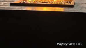 A fire pit with flames, a boat, and a lake in the background.