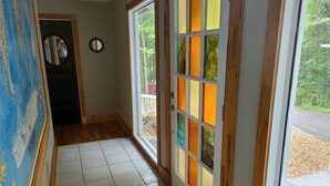 Un couloir doté d’un sol carrelé, d’une porte en bois ornée de panneaux de verre colorés et d’une carte accrochée au mur.