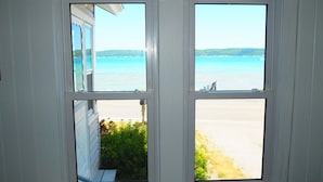 A room with a large window overlooking a beach and the sea. - The Bright and Breezy - Lakefront with Spa! (Frankfort)