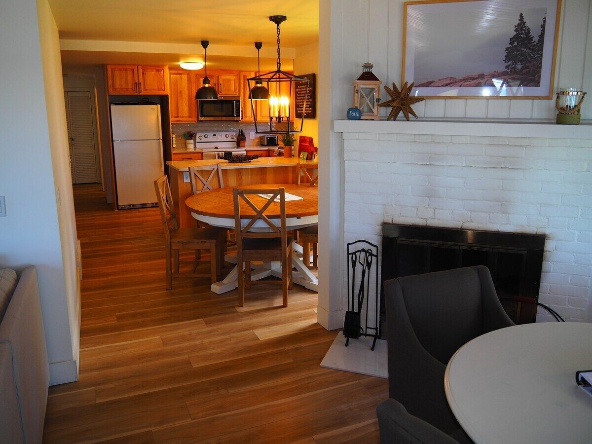 Una cocina con armarios de madera, una isla central y una zona de comedor con una mesa redonda y sillas.