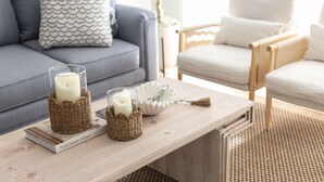 A living room with a wooden coffee table, a grey sofa, and a white armchair.