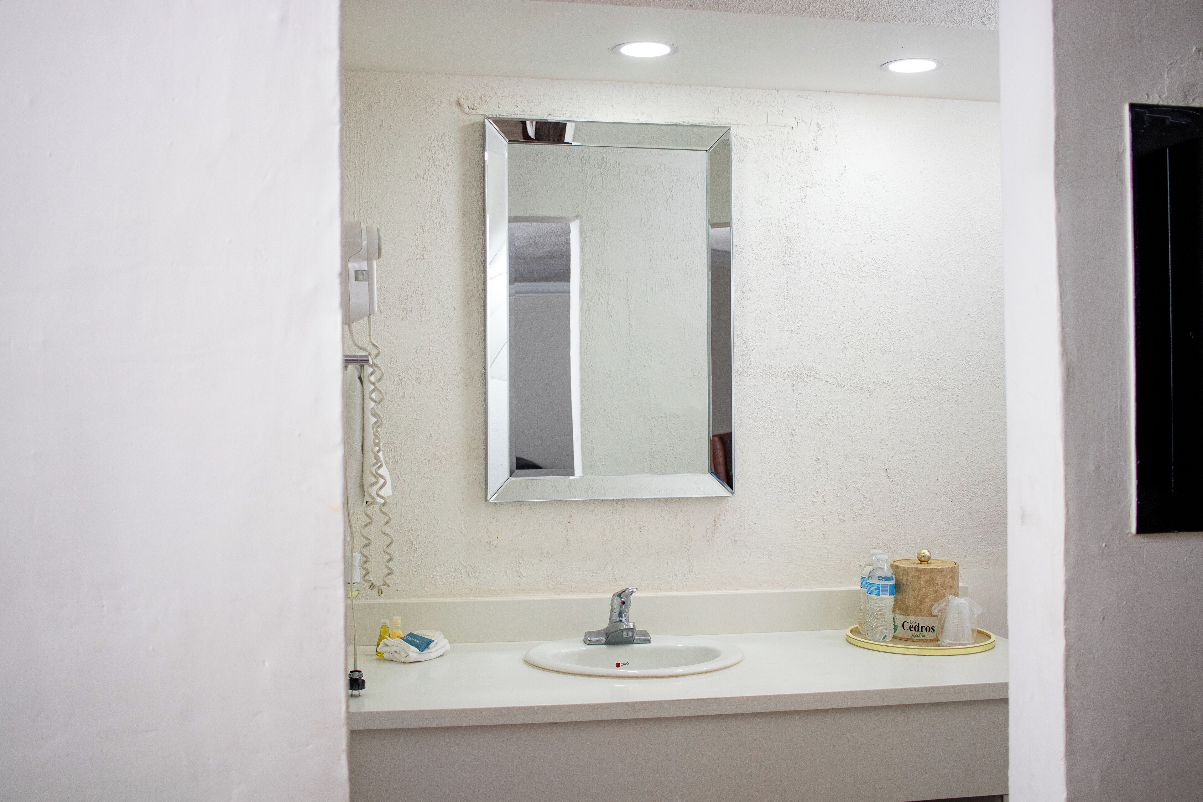 A bathroom with a white sink, a mirror, a telephone, and toiletries on the counter.