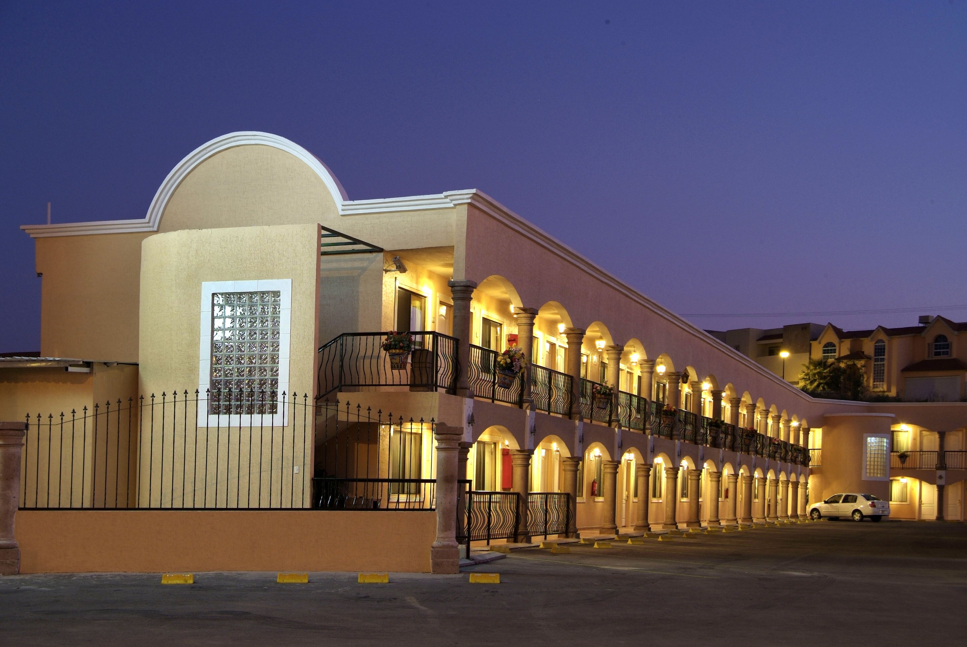 Un hotel con una fachada simétrica, varios balcones y una entrada central.