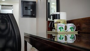 A coffee maker, a tray with coffee mugs, a chair, and a wall-mounted light fixture.