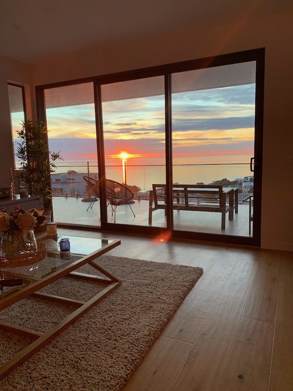 Enjoy a serene view of the water from the balcony, featuring a glass table and a potted plant.