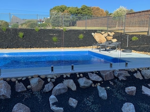 Relax by the pool surrounded by lush gardens and a decorative rock feature.