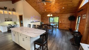 A spacious kitchen with a large island, wooden ceiling, and a dining area with multiple chairs.