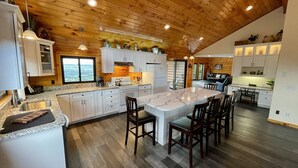 A spacious kitchen with a large island, wooden ceiling, and white cabinetry.
