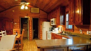 A wooden cabin interior with a kitchen, dining area, and bar. - Modern Private Cabin, Fishing, Shooting Range, Fire Pit, 4WD Trails & Canoeing (Bridgeport)