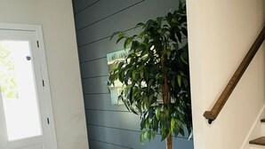 Ein modernes Interieur mit einer Holztreppe, einem Topfpflanzen und einer grauen Wand.