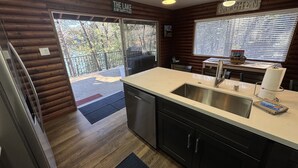 A modern kitchen with wooden walls, a sink, and a window with blinds. - Lakefront #1 Cabin on Acre, Kayaks, Paddle Boards  - Shasta Lakeshore Retreat #4 (Lakehead)