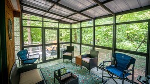 A covered patio with wicker furniture and a view of the forest. - On the Chattahoochee River-Walk to Downtown Alpine Helen (Helen)
