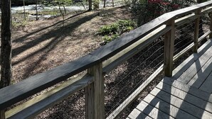 A wooden deck with a metal railing overlooking a forested area with a stream. - On the Chattahoochee River-Walk to Downtown Alpine Helen (Helen)