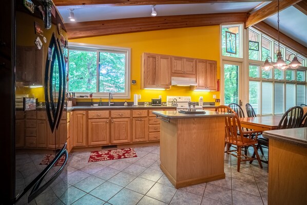 A kitchen with wooden cabinets, a central island, and a dining area with chairs.