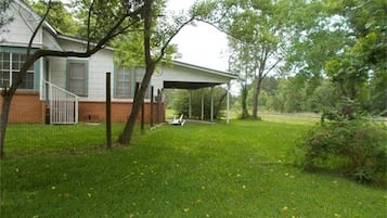 A house with a covered porch, a brick foundation, and a grassy yard.