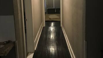 A narrow hallway with a black floor, white walls, and a white door on the left.
