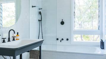 Un baño moderno con piso a cuadros, un espejo grande, un lavamanos con grifo, una ducha con mampara de vidrio y una ventana que proporciona luz natural.
