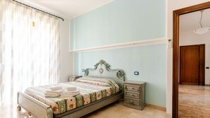 Un dormitorio con cama, mesitas de noche, un aparador y un interruptor de luz en la pared.