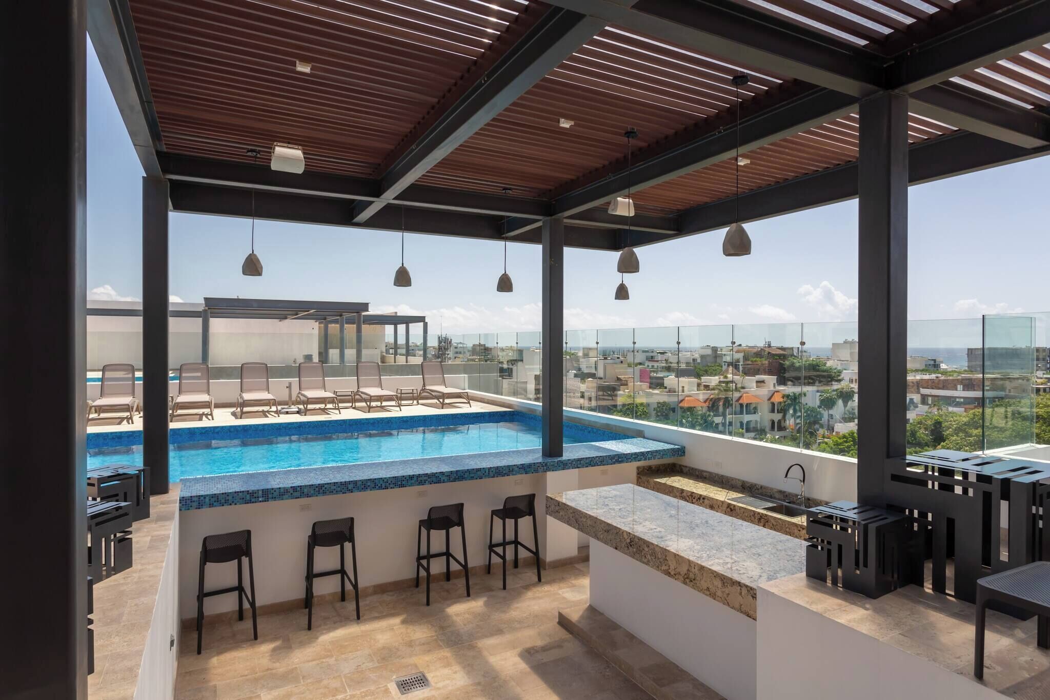 A rooftop bar with a pool, bar stools, and a view of the city.