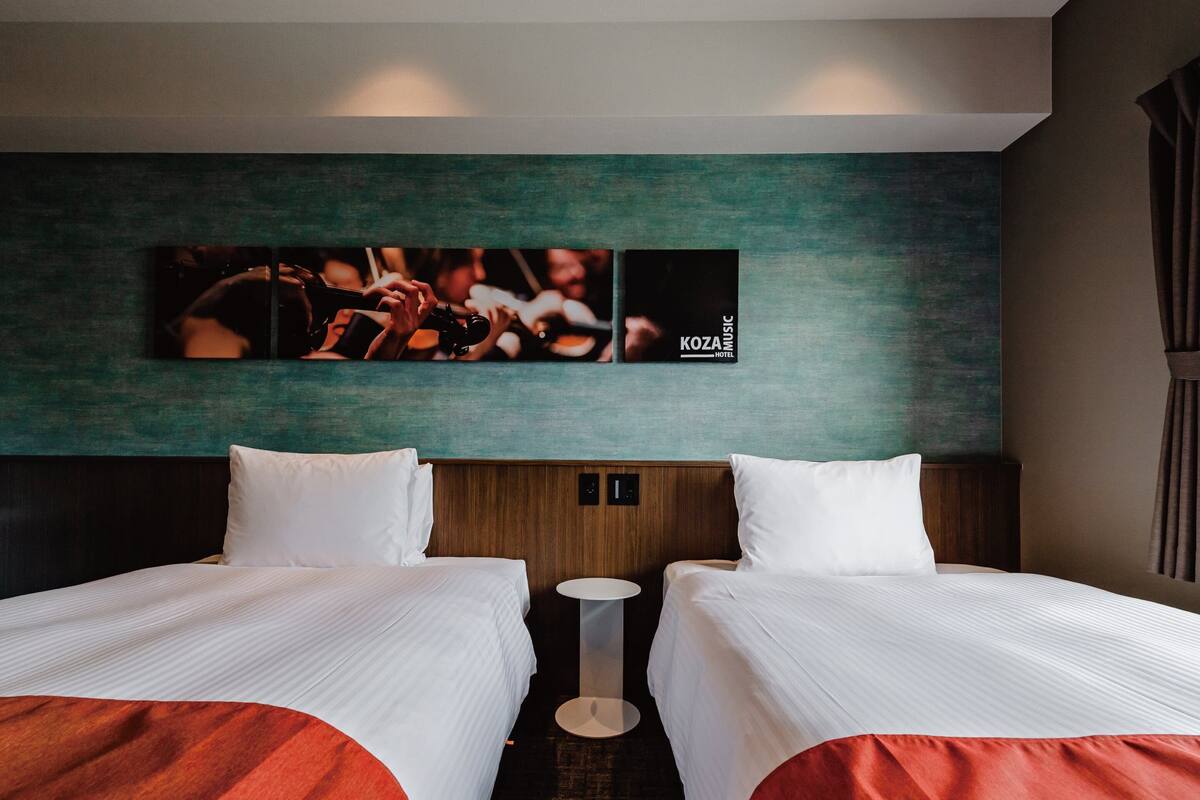 A hotel room with two beds, a small round table, and a large wall art piece.
